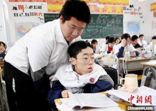 朱金祥(左)把鐘華強放到課堂座位上后，都要把他擺正好，確認安全后才回到自己的座位上。 卓忠偉 攝