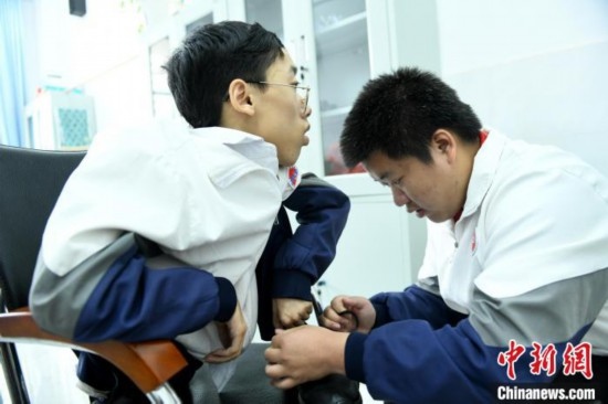江西省南康中學(xué)北校區(qū)的高三學(xué)生朱金祥(右)正在給鐘華強(左)系好鞋帶。 卓忠偉 攝