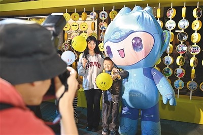5月7日，在浙江省杭州市湖濱步行街“3D笑臉墻”前，攝影師為游客與杭州亞運(yùn)會吉祥物之一“宸宸”拍攝合影。
