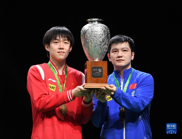 5月27日，樊振東（右）/王楚欽在頒獎(jiǎng)儀式上高舉獎(jiǎng)杯慶祝。當(dāng)日，在南非德班進(jìn)行的2023年世界乒乓球錦標(biāo)賽男雙決賽中，中國(guó)組合樊振東/王楚欽以3比0戰(zhàn)勝韓國(guó)組合張禹珍/林鐘勛，奪得冠軍。新華社記者 李亞輝攝