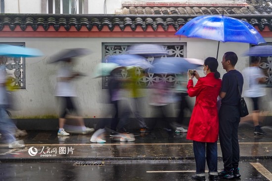 6月7日，在浙江省2023年普通高校招生考試鎮(zhèn)海中學(xué)考點，家長冒雨目送子女進(jìn)入考場。人民網(wǎng) 章勇濤攝