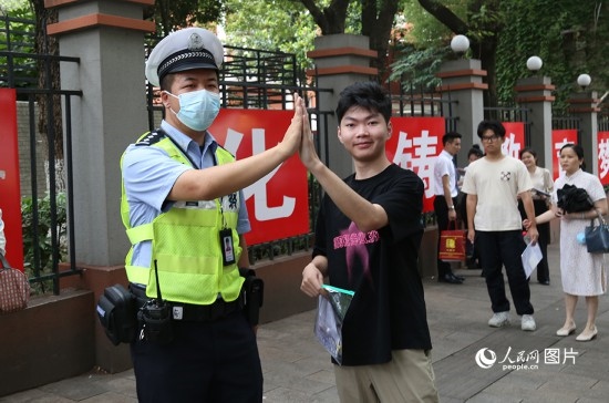 6月7日8時許，武漢中學(xué)考點門口，交警在維護秩序，并祝考生金榜題名。人民網(wǎng)記者 肖璐欣攝