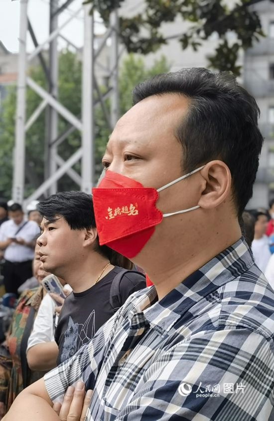 6月7日早，在武漢市第二十六中學(xué)考點外，送考家長戴著印有“金榜題名”的口罩。人民網(wǎng) 周雯攝
