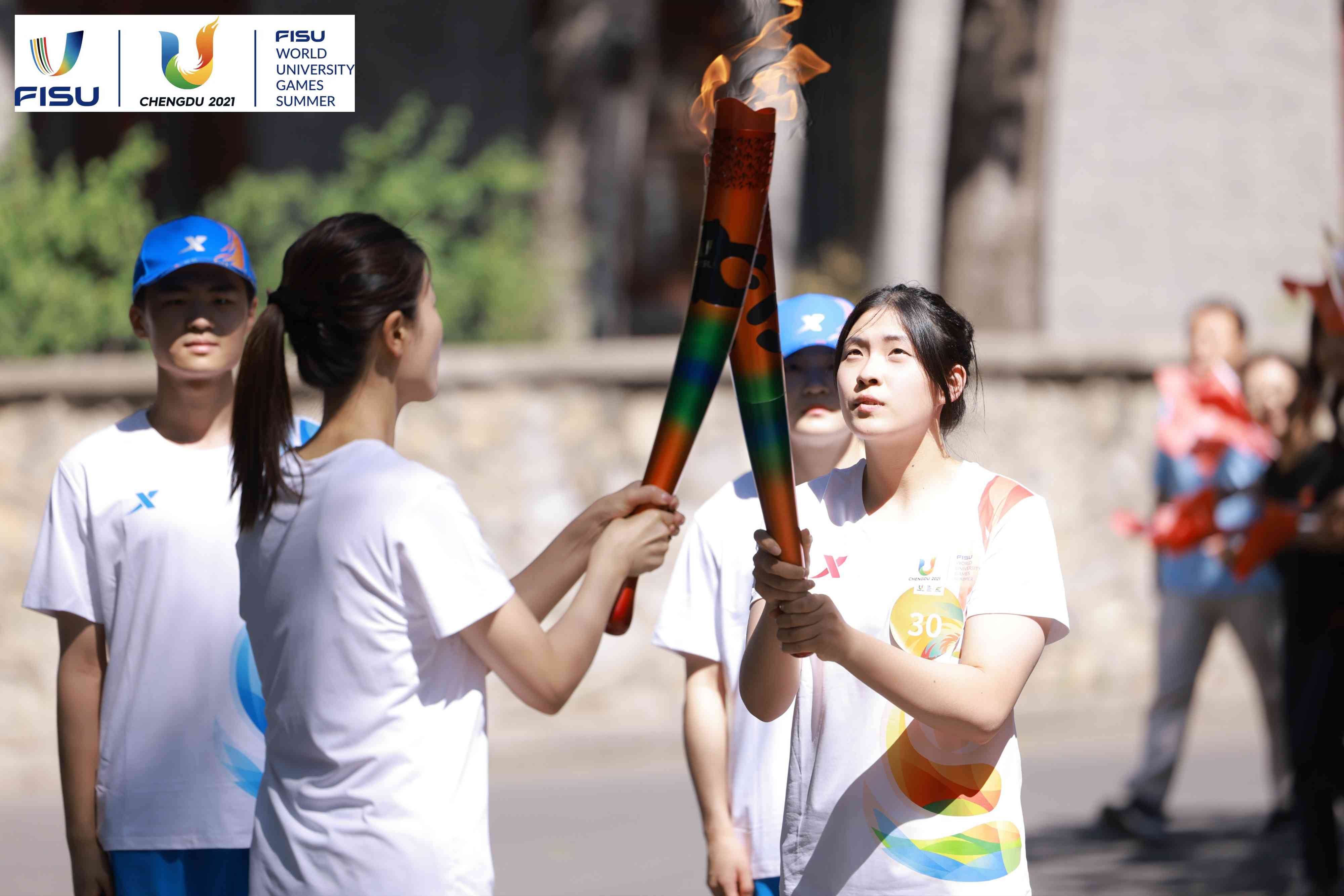 兩名大運(yùn)會(huì)火炬手進(jìn)行火炬?zhèn)鬟f。 圖片來源：成都大運(yùn)會(huì)執(zhí)委會(huì)供圖