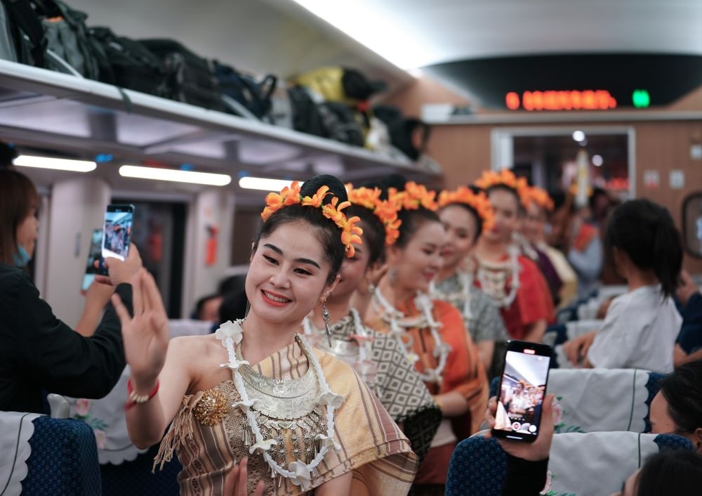 2023年4月13日，老撾工作人員在D887次國際旅客列車上表演。當日，中老鐵路從中國昆明南站、老撾萬象站雙向?qū)﹂_D887次和D888次國際旅客列車，兩地乘火車可當日通達。中老鐵路是高質(zhì)量共建“一帶一路”的標志性工程。新華社記者 邢廣利 攝