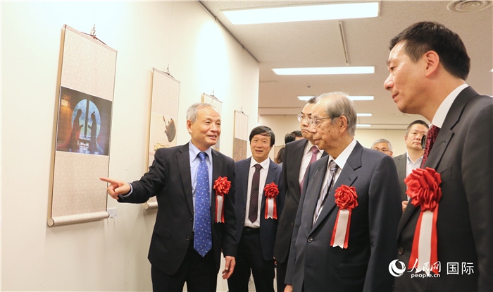 “湖州印象”攝影展主創(chuàng)、世界華人攝影協(xié)會(huì)副會(huì)長(zhǎng)馮學(xué)敏向吳江浩大使、福田康夫前首相等嘉賓介紹展出作品。（人民網(wǎng) 許可攝）