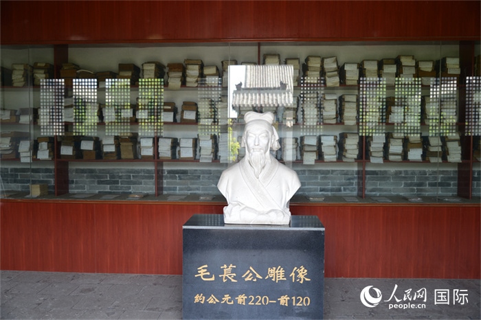 河間詩(shī)經(jīng)齋毛萇雕像。雕像后書(shū)櫥中陳列的是歷代各版本《詩(shī)經(jīng)》及譯本。 人民網(wǎng) 趙昭攝