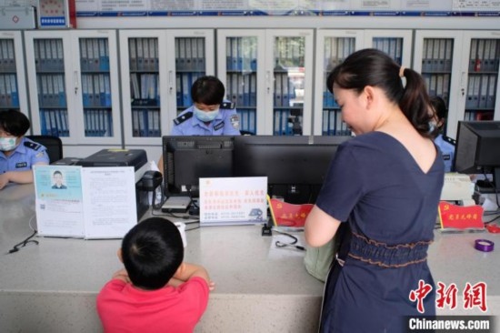 圖為一名家長正在辦證窗口前為孩子申領居民身份證。劉俊聰 攝