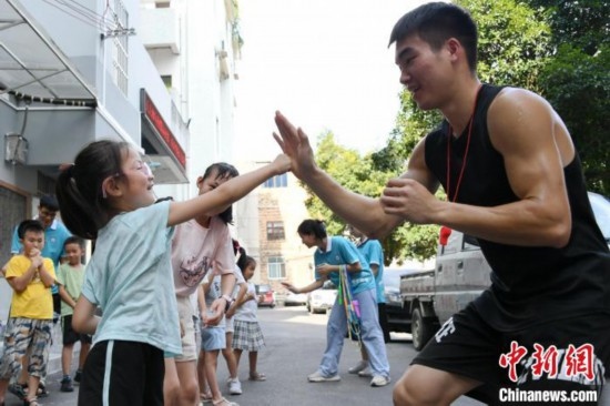 圖為大學(xué)生志愿者在組織孩子們參加體育健身活動。廖光福 攝