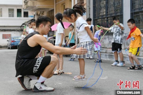 圖為大學(xué)生志愿者在教孩子們學(xué)跳繩。廖光福 攝