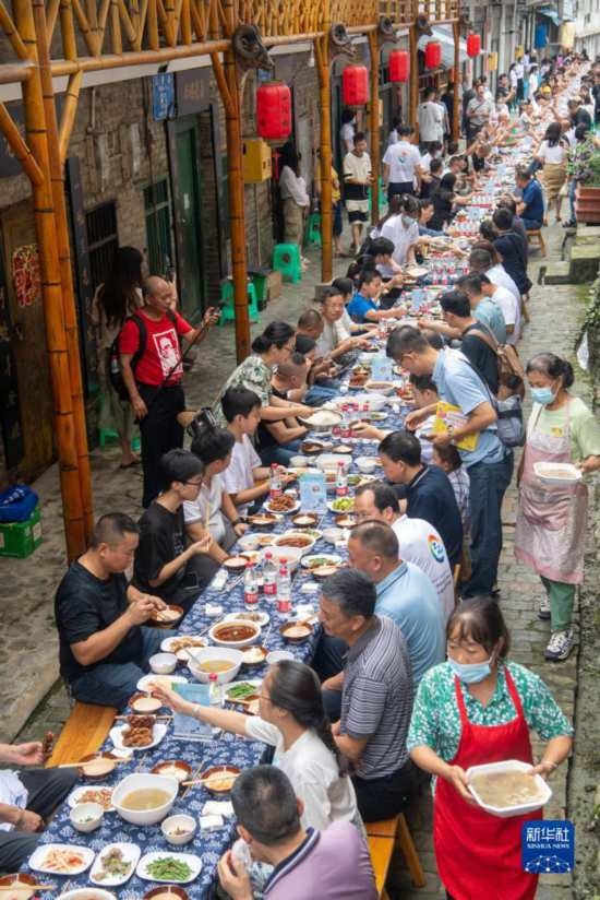 7月29日，在重慶市綦江區(qū)安穩(wěn)鎮(zhèn)，人們在“苗家伏羊節(jié)”上吃長桌宴。新華社記者 唐奕 攝