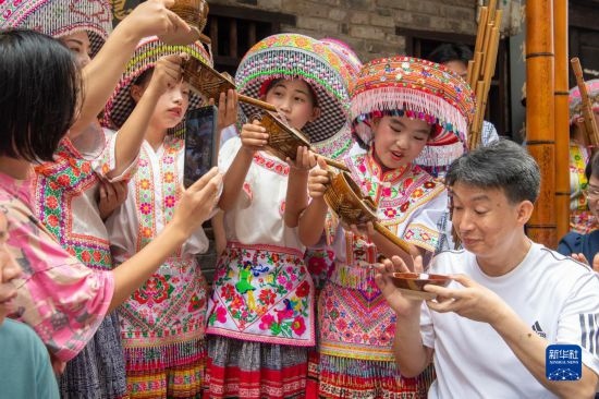 7月29日，在重慶市綦江區(qū)安穩(wěn)鎮(zhèn)，當(dāng)?shù)鼐用裨凇懊缂曳蚬?jié)”上用傳統(tǒng)習(xí)俗向游客表達祝福。新華社記者 唐奕 攝