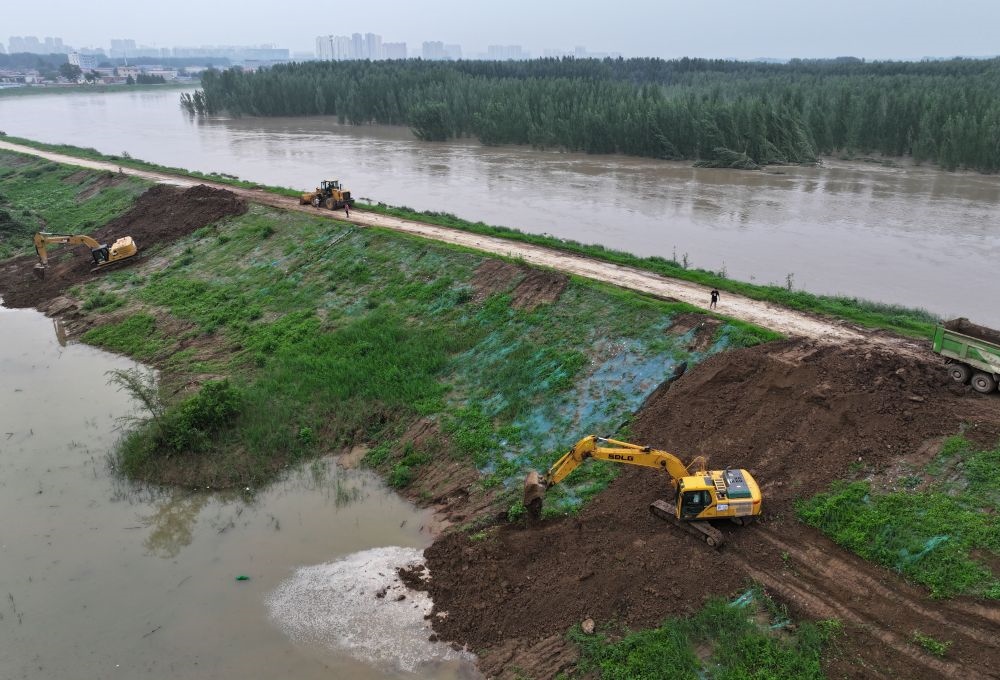 工人操作機械在白溝河左堤白溝新城高橋村段進行除險加固作業(yè)（8月4日攝，無人機照片）。新華社記者 朱旭東 攝