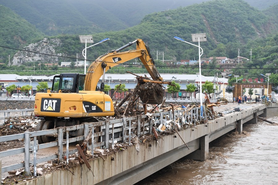 8月1日，在北京市門頭溝區(qū)水峪嘴村村口，一臺(tái)挖掘機(jī)在清理阻斷橋梁交通的雜物。目前該條道路已經(jīng)疏通完成。新華社記者 鞠煥宗 攝