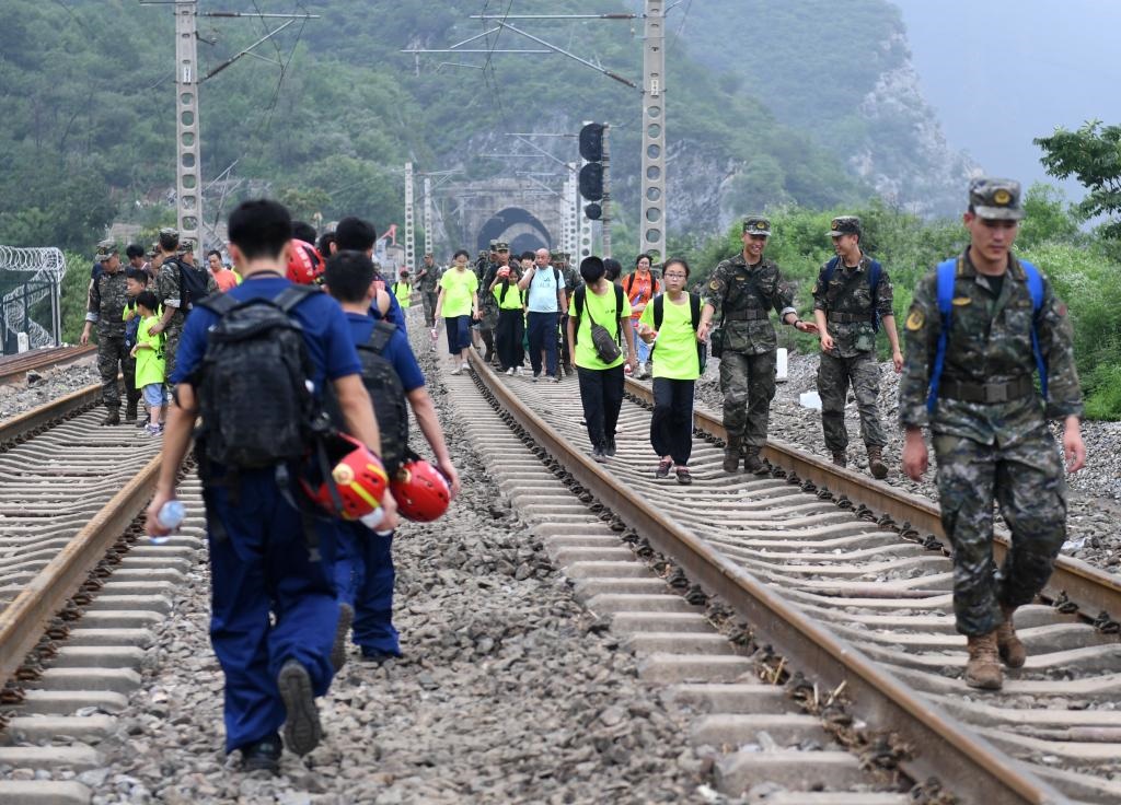 8月2日，部分滯留在北京市門頭溝山區(qū)受困列車的旅客，在救援人員幫助下前往轉(zhuǎn)運客車。新華社記者張晨霖 攝