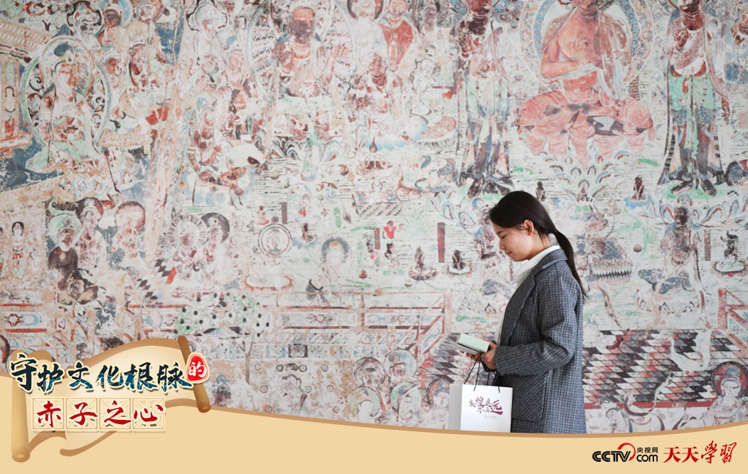 2023年4月25日，敦煌研究院文物數(shù)字化保護(hù)團(tuán)隊創(chuàng)意營銷人員廖雪婷從一幅高保真復(fù)制壁畫前走過。