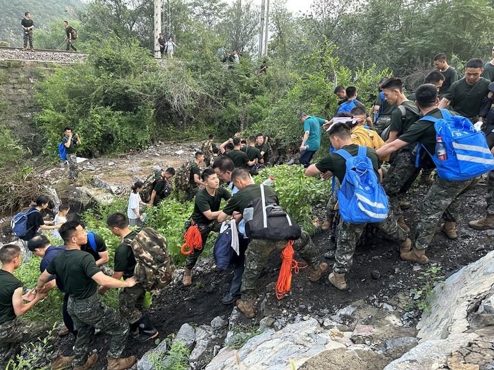 8月2日，Z180次受困列車的旅客在武警北京總隊(duì)機(jī)動(dòng)第三支隊(duì)官兵的幫助下徒步前往轉(zhuǎn)運(yùn)客車（手機(jī)照片）。新華社記者 王艷剛 攝
