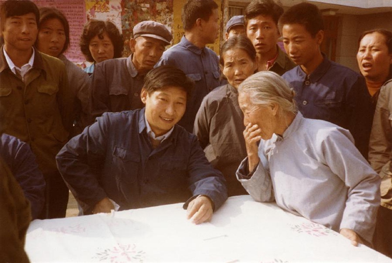 1983年，時(shí)任河北正定縣委書記的習(xí)近平（前排居中）臨時(shí)在大街上擺桌子聽取老百姓意見。