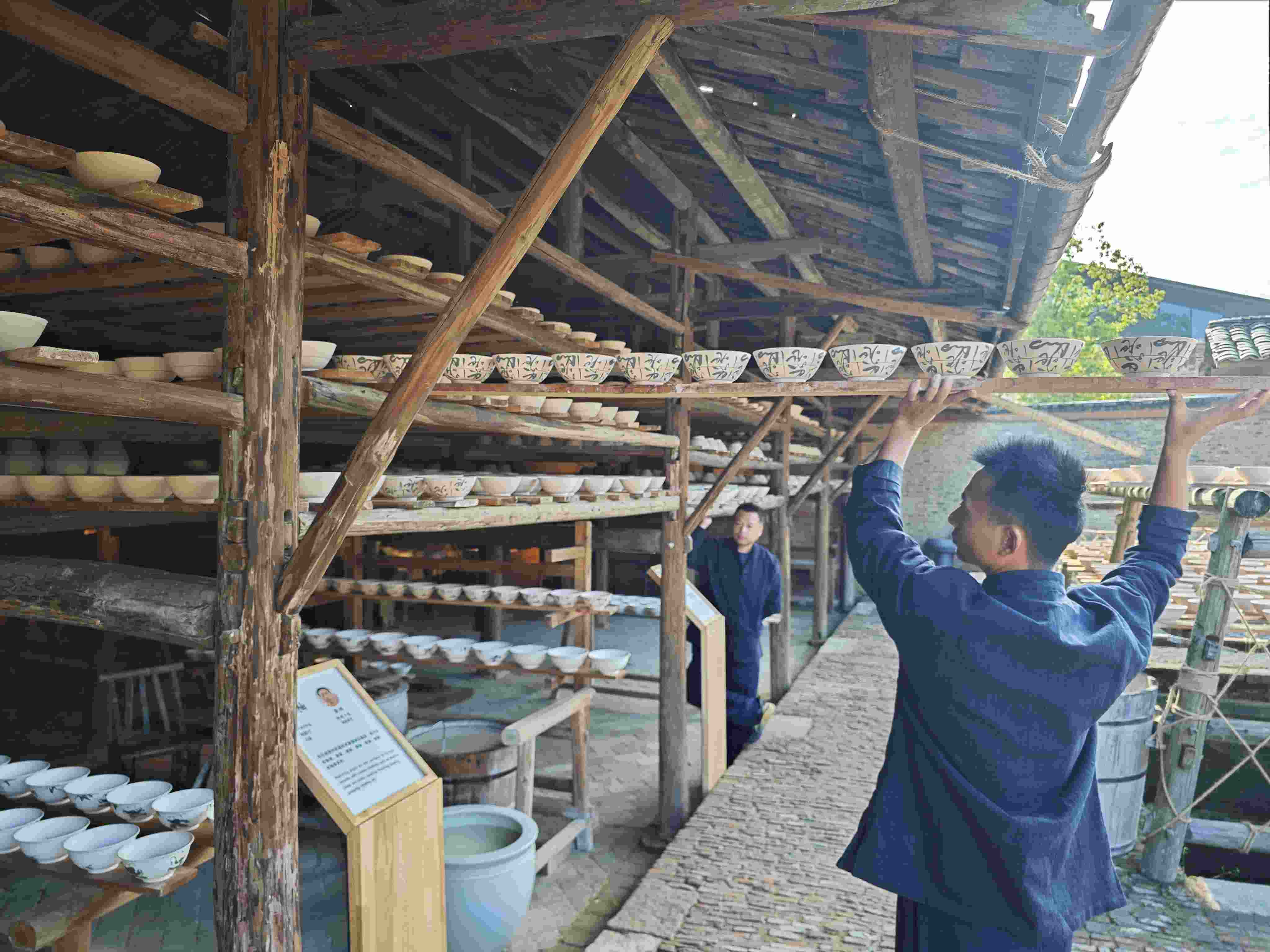 △陶陽里歷史文化街區(qū)里，工匠將陶瓷工藝品放到架上晾干。（總臺(tái)央視記者彭漢明拍攝）