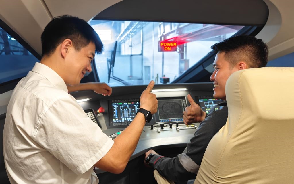 8月25日，在印度尼西亞萬隆的雅萬高鐵德卡魯爾動車所內，中國師傅穆振（左）在向印尼火車司機塞蒂亞萬講解動車組出庫前的上電作業(yè)。