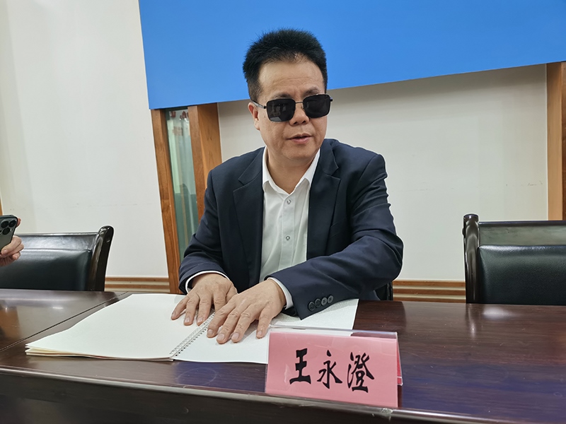 全國人大代表王永澄正在閱讀盲文版代表建議答復(fù)。本報記者 張 璁?dāng)z