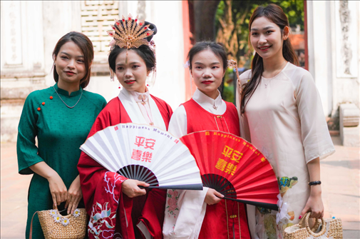身穿古裝的中國(guó)游客和身穿越南傳統(tǒng)服飾奧黛的越南青年在文廟門(mén)前合影。