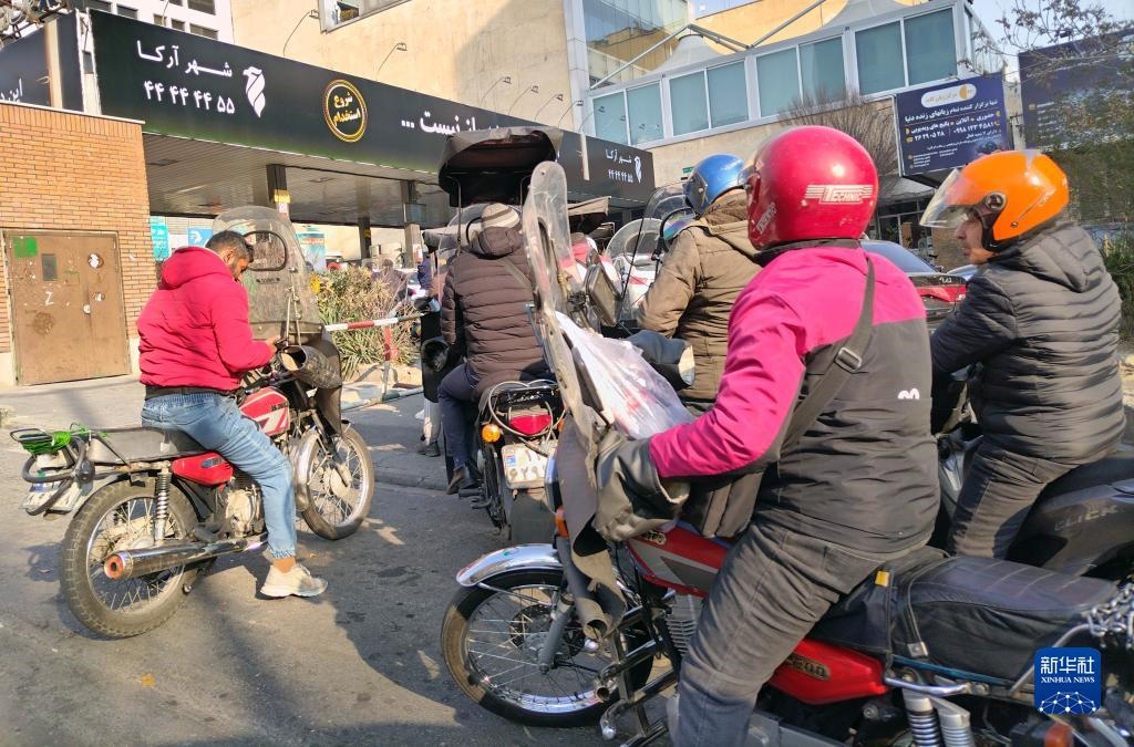 12月18日，摩托車在伊朗首都德黑蘭的一家加油站外等待加油。新華社記者 沙達提 攝
