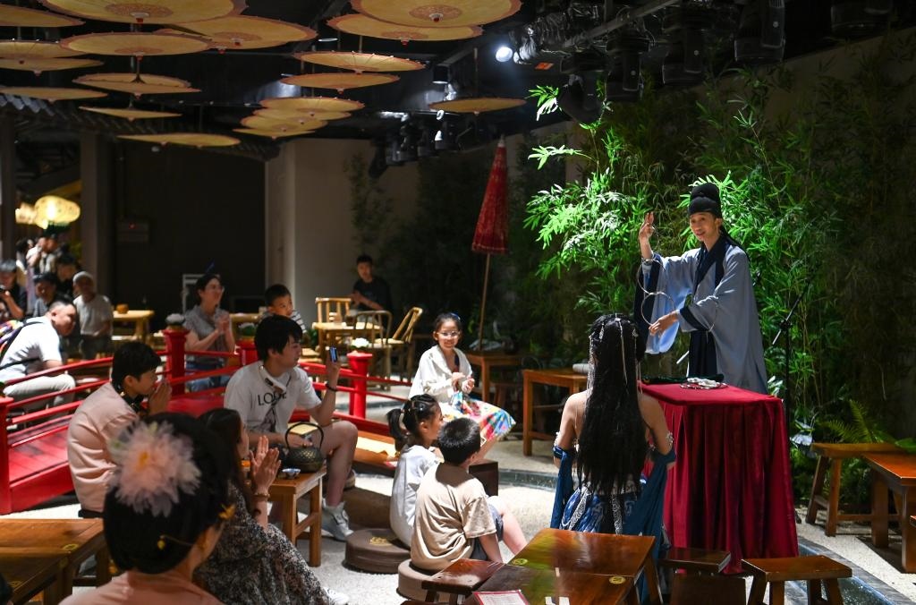 游客在長(zhǎng)安十二時(shí)辰主題街區(qū)觀看唐風(fēng)演藝《大唐曲藝》。新華社記者鄒競(jìng)一 攝