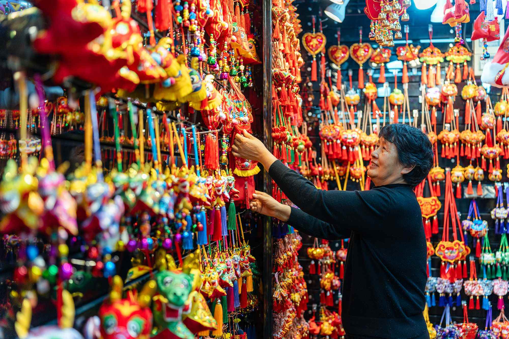 2023年12月11日，金華義烏國(guó)際商貿(mào)城，龍年喜慶用品掛滿(mǎn)攤位，顧客正在挑選中。