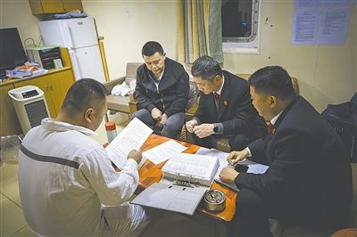 圖②：法官向船長講解相關(guān)法律規(guī)定，查看船舶資料，并與船方辦理扣押船舶的手續(xù)。