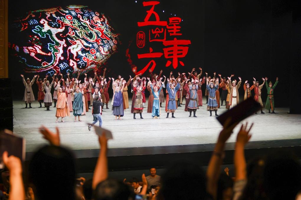 2023年7月31日，新疆和田地區(qū)新玉歌舞團(tuán)在烏魯木齊京劇院演出舞劇《五星出東方》后和觀眾互相揮手致意。這場(chǎng)演出是第六屆中國(guó)新疆國(guó)際民族舞蹈節(jié)的參演劇目之一，曾榮獲國(guó)家“文華獎(jiǎng)”等。新華社記者 郝昭 攝