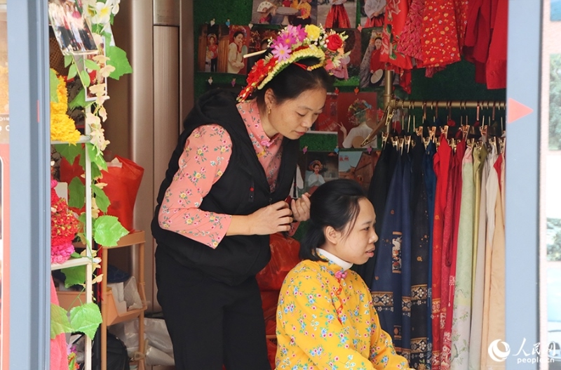 泉州府文廟附近，一名店主正為過(guò)路游客梳理頭發(fā)以佩戴“簪花圍”。人民網(wǎng) 黃東儀攝