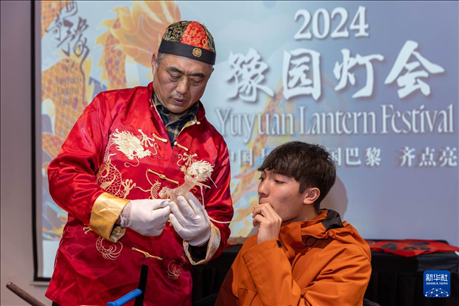 1月28日，在上海豫園舉行的民俗活動上，美國馬斯卡廷中學(xué)學(xué)生在非遺傳承人的指導(dǎo)下吹糖偶。 新華社記者 王翔 攝