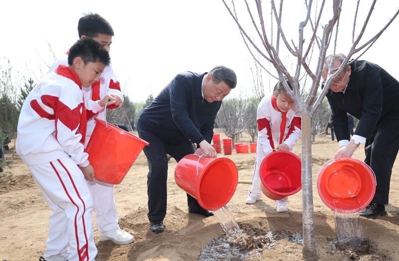 2024年4月3日，習(xí)近平總書記同少先隊員一起給剛栽下的樹苗澆水。