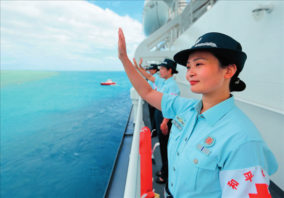 中國(guó)海軍“和平方舟”號(hào)醫(yī)院船結(jié)束訪問湯加時(shí)，任務(wù)官兵中的文職人員向歡送人群揮手告別（2023年8月4日攝）。徐巍攝/本刊