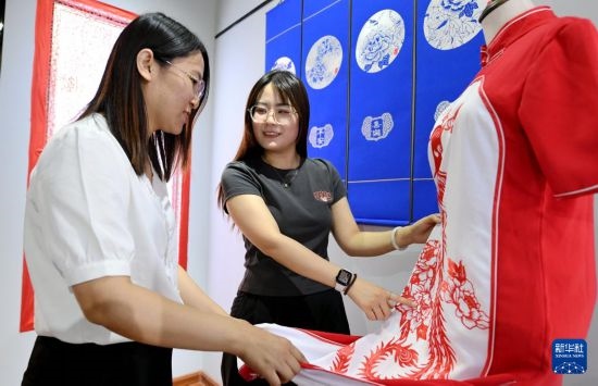 5月31日，在衡水市阜城縣一家剪紙工作室，游客在觀賞帶有剪紙?jiān)氐钠炫邸? width=