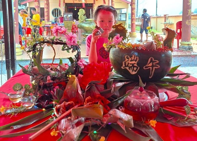 小朋友展示學(xué)裹粽子的成品照。組委會供圖