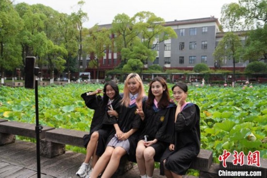 6月19日，時值一年畢業(yè)季，四川大學(xué)望江校區(qū)荷花池里的荷花盛開，成為了畢業(yè)生們的打卡圣地，吸引了眾多畢業(yè)生拍照留念。圖為畢業(yè)生在荷花池邊拍照留念。中新社記者 安源 攝