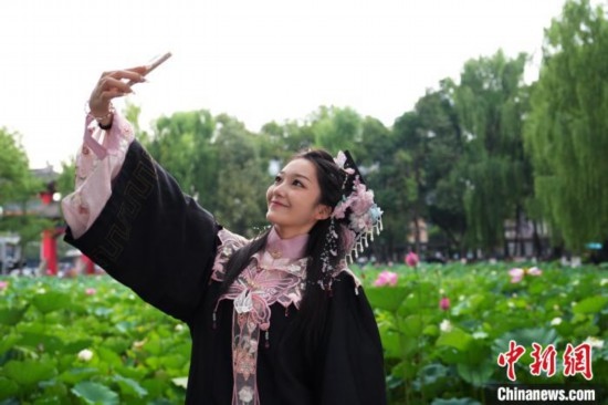 6月19日，時值一年畢業(yè)季，四川大學(xué)望江校區(qū)荷花池里的荷花盛開，成為了畢業(yè)生們的打卡圣地，吸引了眾多畢業(yè)生拍照留念。圖為畢業(yè)生在荷花池邊拍照留念。中新社記者 安源 攝