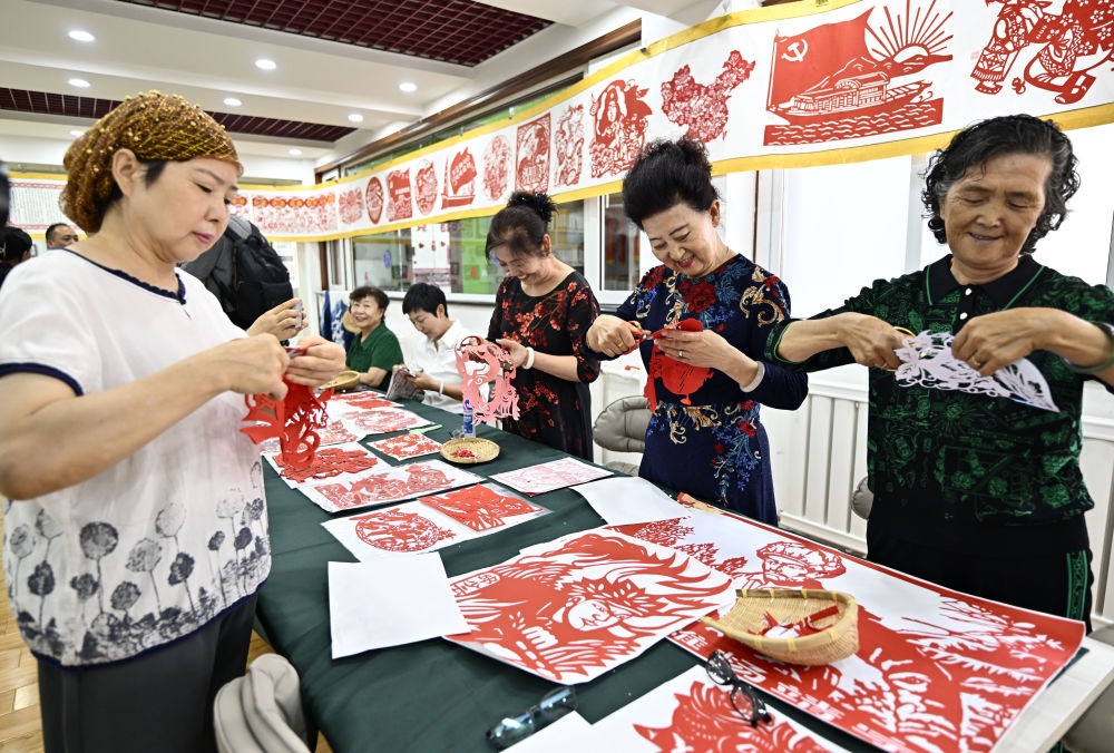 6月19日，長(zhǎng)城花園社區(qū)居民在社區(qū)“才藝堂”制作剪紙。