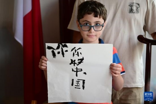 7月4日，在馬耳他桑塔露琪亞市的中國古典園林“靜園”，一名男孩展示他的書法作品。新華社發(fā)（喬納森·博格 攝）