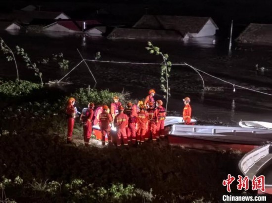  7月6日凌晨3時，在湖南岳陽華容縣團(tuán)洲垸洞庭湖一線堤防，救援人員剛剛完成一次救援任務(wù)，遠(yuǎn)處是被淹的民房。中新社記者 白祖偕 攝