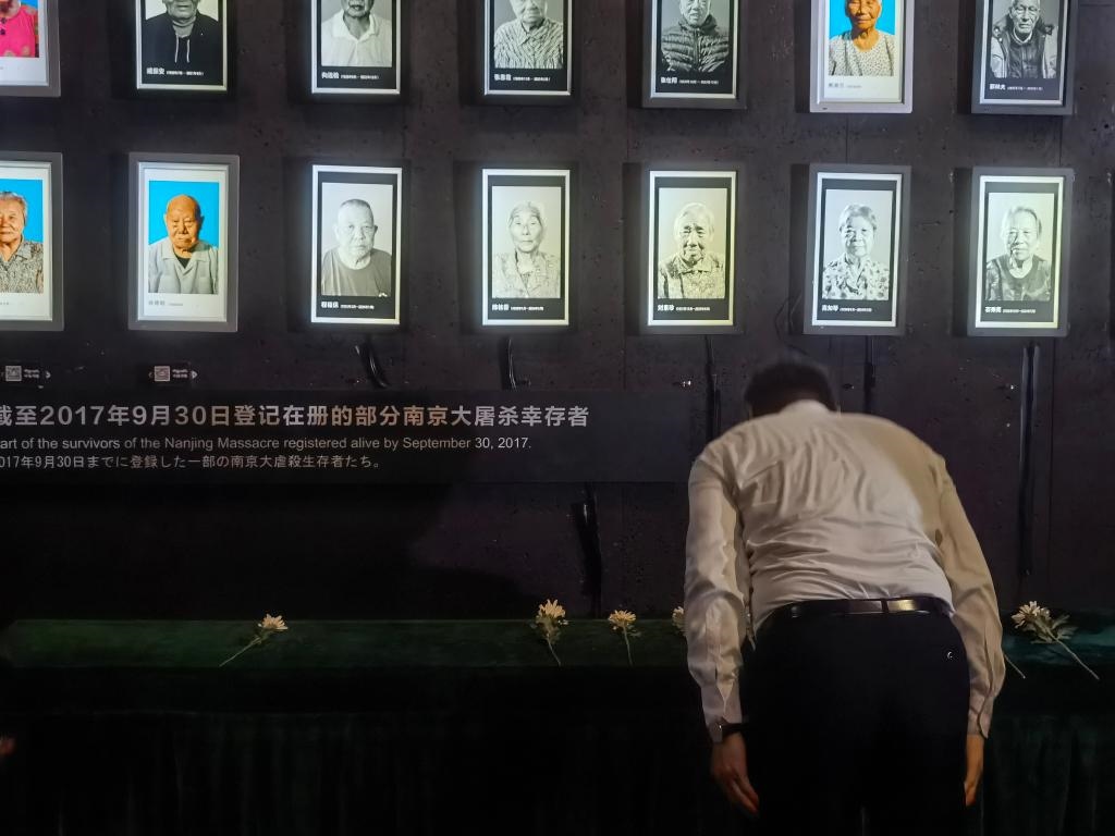 7月18日，人們向離世的南京大屠殺幸存者獻(xiàn)花、鞠躬。新華社記者邱冰清 攝