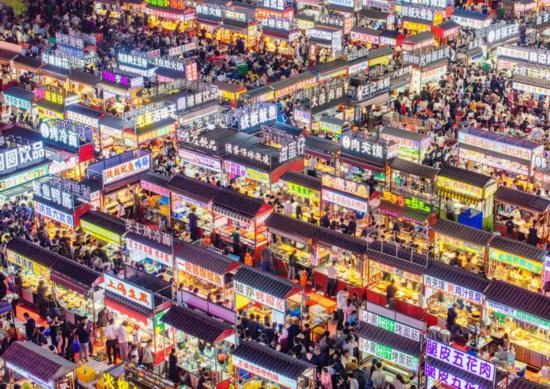 2024年4月21日，人們?cè)诤颖笔≌h小商品夜市品嘗美食（無(wú)人機(jī)照片）。新華社發(fā)（武志偉 攝）