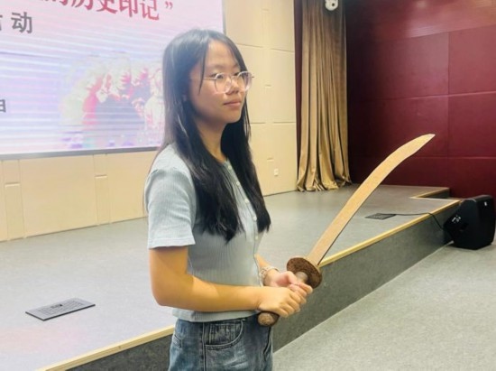 圖為南開大學(xué)社會(huì)實(shí)踐隊(duì)學(xué)生代表呼月紅在學(xué)術(shù)交流活動(dòng)現(xiàn)場(chǎng)，展示河間調(diào)研行中獲贈(zèng)的一戰(zhàn)華工蔡世春曾使用過的一把大刀。林卓瑋 攝