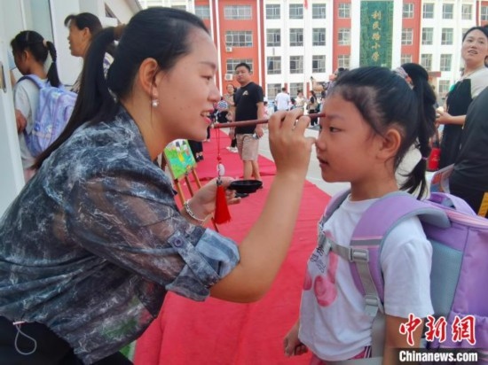 圖為衡水市利民路小學，老師為學生點朱砂痣，寓意開啟智慧。張松 攝