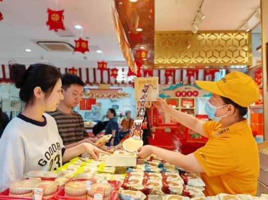 北京稻香村一家門店內(nèi)，售貨員向顧客展示新上市的月餅禮盒。（受訪者供圖）
