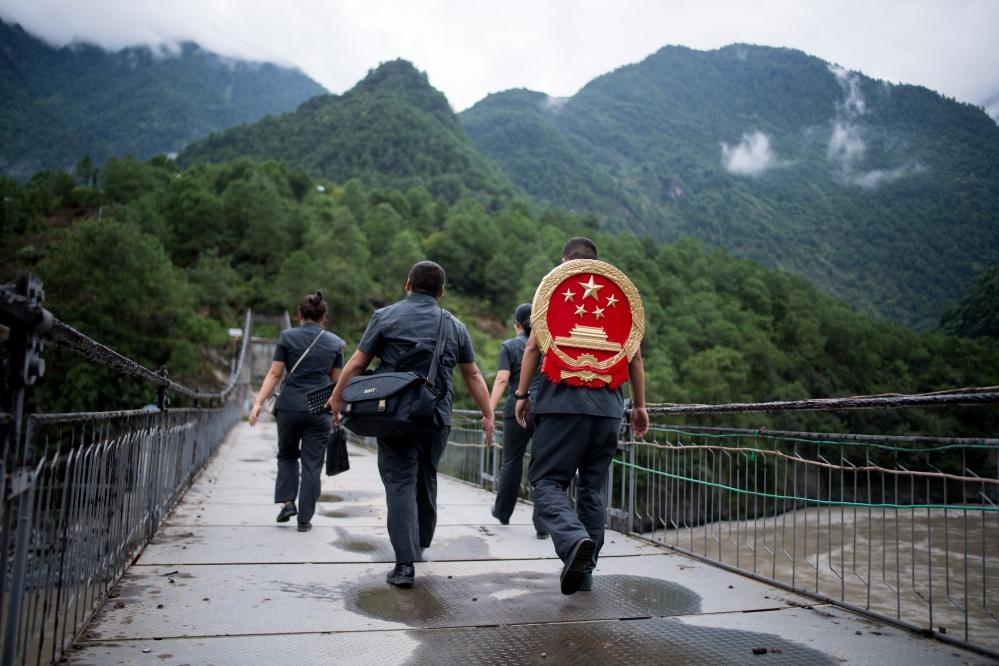 云南省怒江傈僳族自治州貢山縣人民法院法官鄧興背著國徽與同事們跨過怒江（2019年8月30日攝）。怒江高山峽谷眾多，交通不便，為方便群眾、更好地開展法律服務，背著國徽攀高山、過索橋、躲落石、鉆老林……成為鄧興法官的工作常態(tài)。新華社記者 江文耀 攝