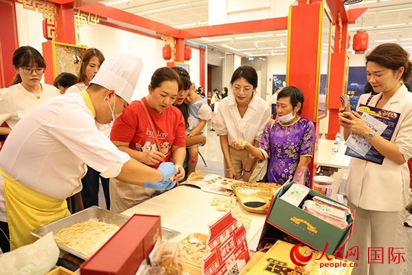 演出前，在天津桂發(fā)祥十八街麻花制作技藝非遺體驗(yàn)展臺(tái)前，泰國民眾體驗(yàn)天津麻花制作。人民網(wǎng)記者 楊一攝