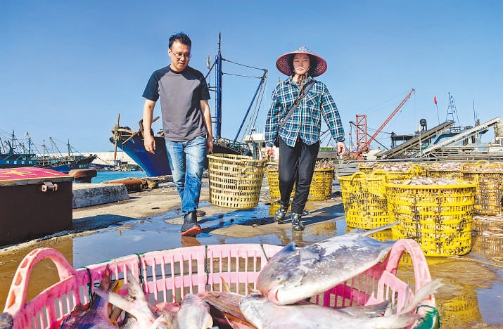 許小斌（左）和漁民一起搬運(yùn)海鮮。本報(bào)記者 付 文攝